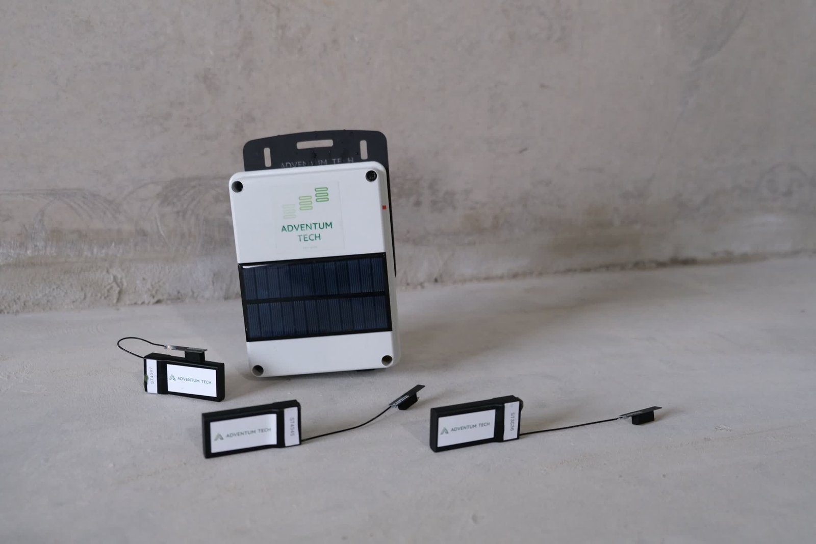 Tempsense Pro Lora devices Adventum Tech TempSense Pro LoRa devices by Adventum Tech, featuring a solar-powered unit and three sensor modules on a concrete surface.